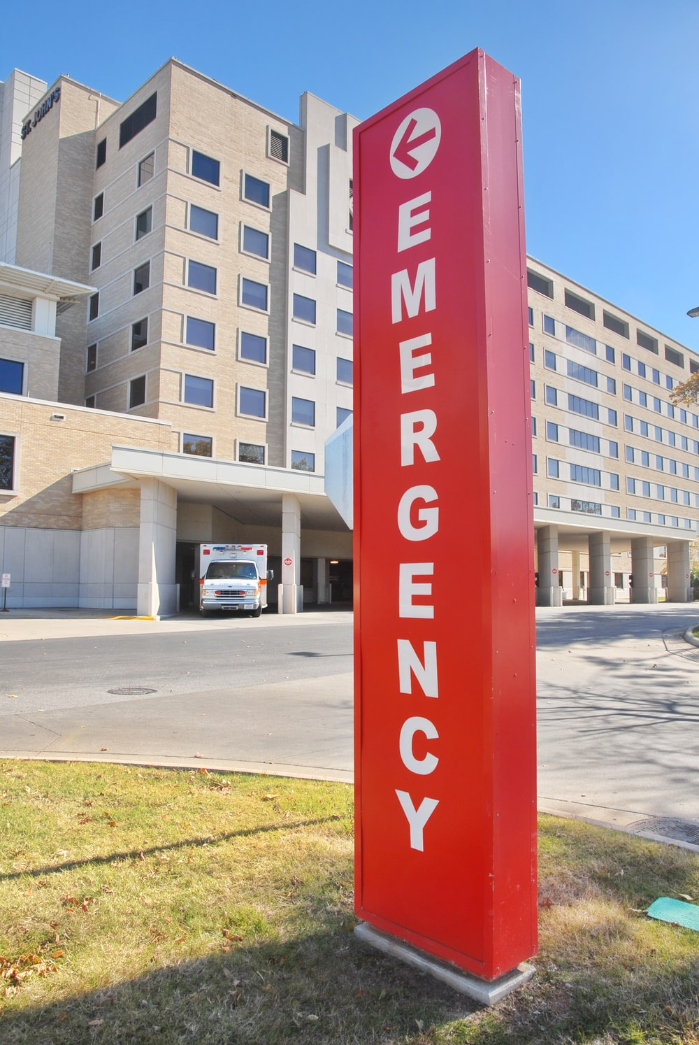 An ambulance parked near a hospital’s emergency sign
