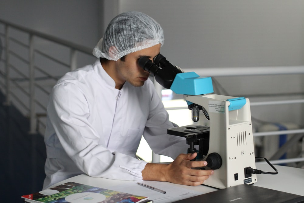 man sighting on white microscope